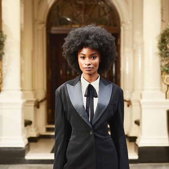 A lady dressed in a smart suit stands in front of the Connaught